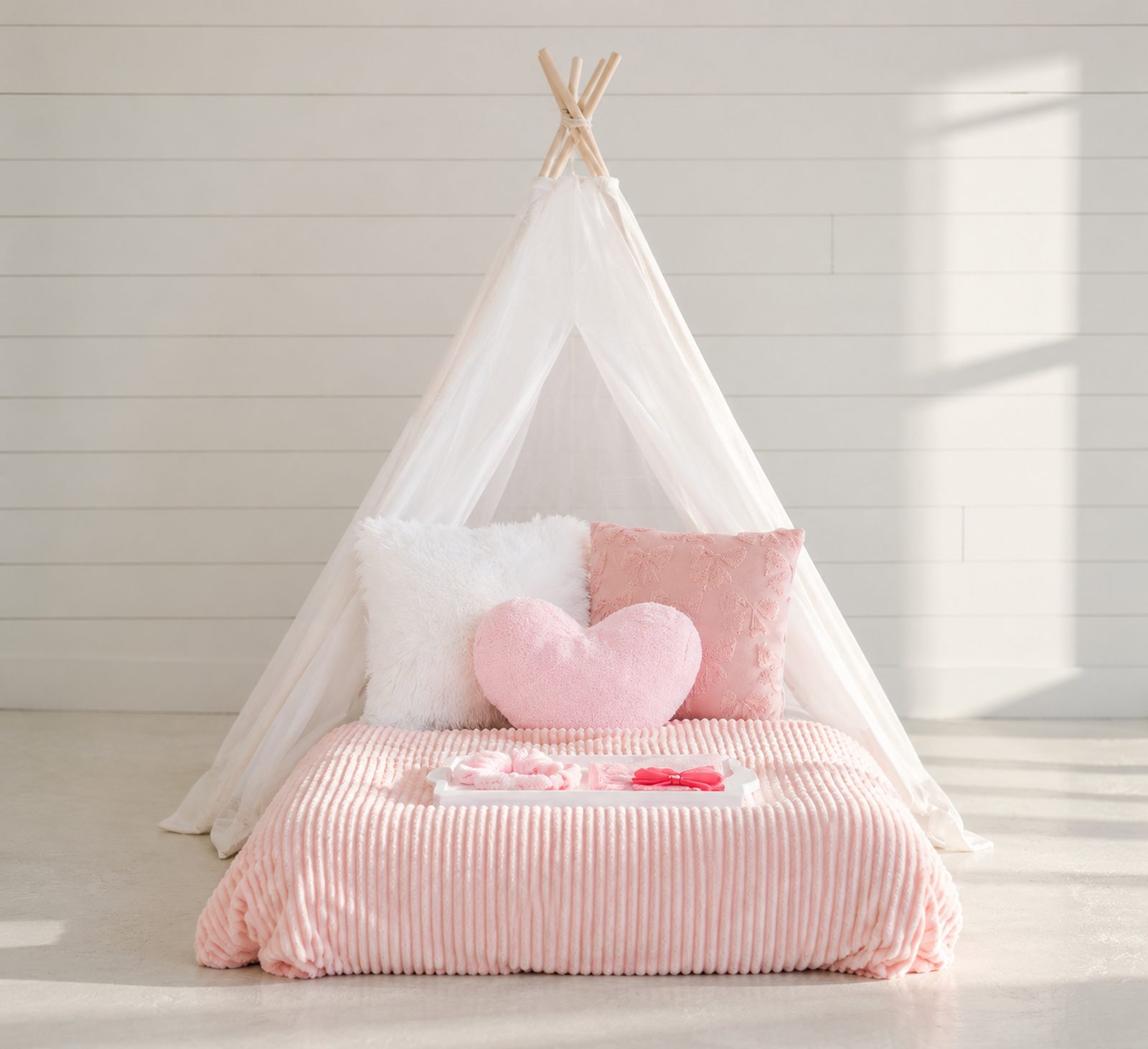 A single pink teepee bed with heart pillows
