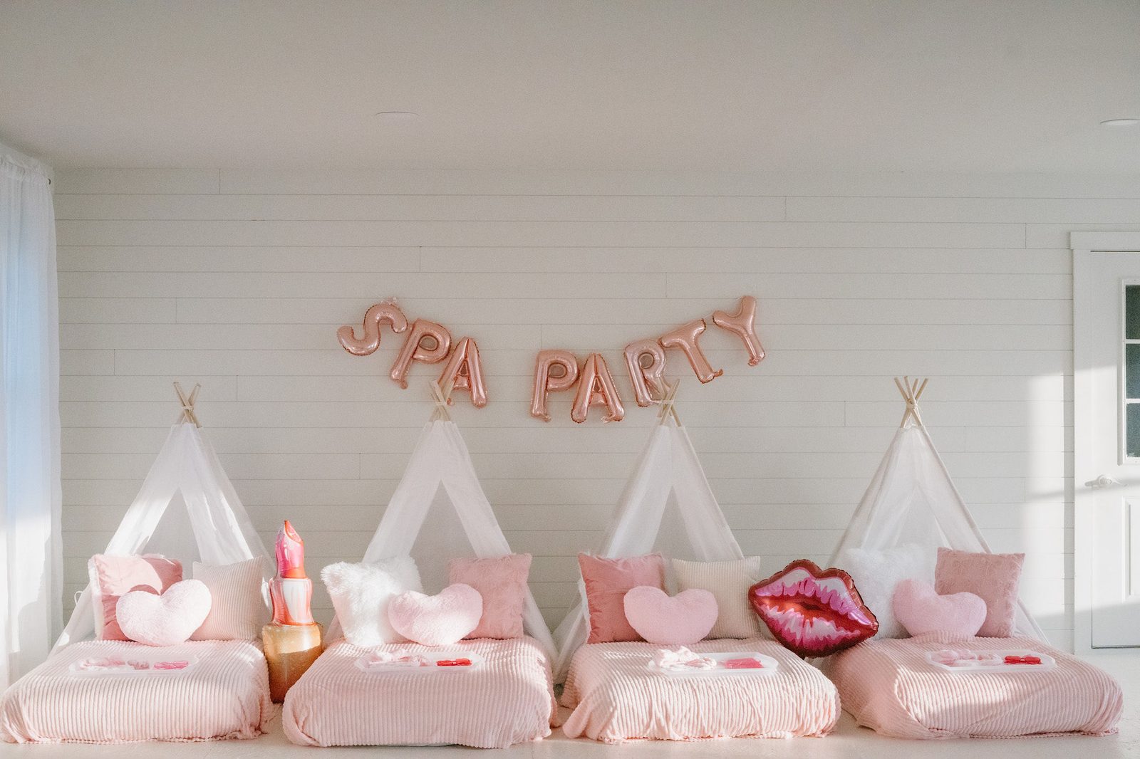Four pink teepee beds under a SPA PARTY banner